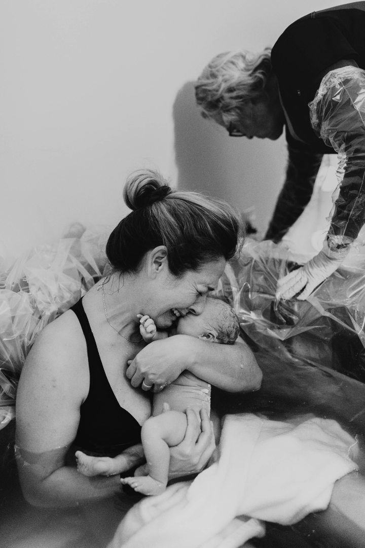 Mom holding baby in a birth tub after water birth